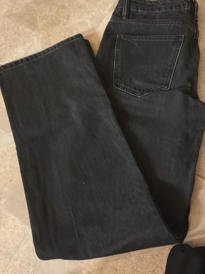 Svarta raka jeans med hög midja - Säljer ett par svarta jeans med rak passform och hög midja. Jeansen har klassiska fem fickor och är tillverkade i ett kraftigt denimtyg. Perfekta för en avslappnad och trendig look.  Pris: 175 +frakt