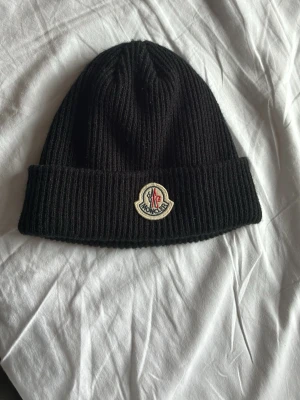 Moncler mössa  - Säljer en svart Moncler mössa för att den knappt kom till någon användning, säljer den för mycket bra pris!