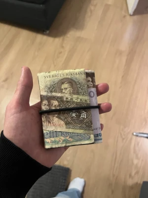 Hemmagjord plånbok med gummiband - Säljer en unik hemmagjord plånbok som är gjord av äkta sedlar och hålls ihop med ett svart gummiband. Sedlarna är alla äkta och är från olika delar av världen, alltifrån Kina, Sverige och Polen. Har tagit inspiration från Maison Margielas 11 dollar wallet.