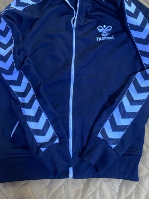 Svart Hummel träningsjacka - Det är en svart Hummel träningsjacka. Den är använd cirka 3 gånger. Den är i storlek L men skulle säga att den kan användas för någon som har högre eller mindre storlek. Den är perfekt för någon som vill ha en sportig fit. Pris går att diskutera 💕