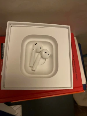 Apple AirPods trådlösa hörlurar - Säljer ett par vita Apple AirPods med stilren och minimalistisk design. Hörlurarna är trådlösa och har en slimmad form som sitter bekvämt i öronen. Tillverkade i blank plast och levereras i originalförpackning.
