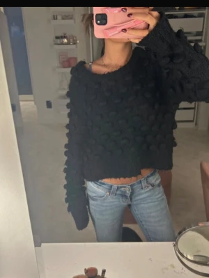 Svart  stickad tröja - Säljer en svart chunky stickad tröja med stora bollar över hela tröjan. Tröjan har en croppad passform, bred halsringning och långa ärmar. Perfekt för dig som gillar en unik och trendig look . 