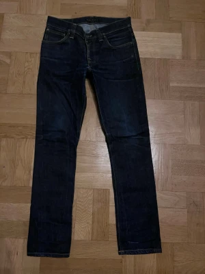 Nudie Jeans Grim Tim – Mörkblå – Superfint skick 💙👖 - Säljer mina Nudie Jeans Grim Tim i en jättefin mörkblå färg. Modellen är slim straight och sitter så snyggt – perfekta både till vardags med sneakers eller lite mer uppklätt ✨  De är i riktigt fint skick, och inte använda och väl omhändertagna. Inga hål eller tråkiga slitningar, bara lite naturliga veck som ger den där snygga denimkänslan 💕  Superbra kvalitet och ett par tidlösa jeans som man kan ha hur länge som helst! Skriv om du undrar något eller vill ha fler bilder 🥰