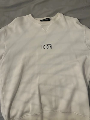 Vit sweatshirt från Dsquared2 ICON - Vit sweatshirt från Dsquared2 med svart 'ICON'-tryck på bröstet. Klassisk rund halsringning och avslappnad passform.