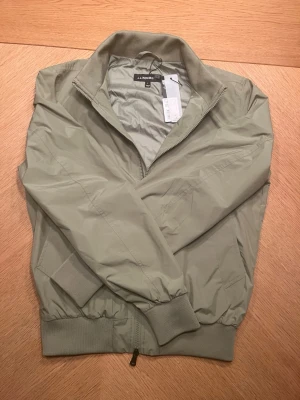 Ljusgrön vindjacka från J.Lindeberg - Ljusgrön jacka från J Lindeberg. Helt ny med lapp kvar. Nypris är ca 3000. Perfekt för våren eller hösten. 