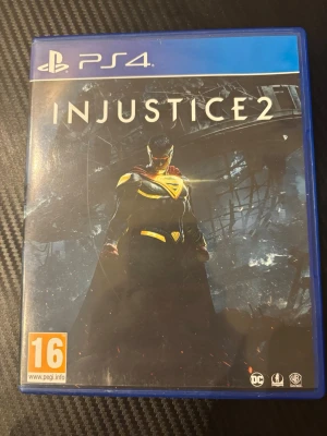 Injustice 2 till PS4 - Injustice 2 till PlayStation 4 är ett fightingspel där du kan spela som olika DC Comics-hjältar och skurkar. Spelet kommer i ett blått plastfodral med omslag och originalskiva. Omslaget har en mörk, dramatisk design med en superhjälte i centrum.