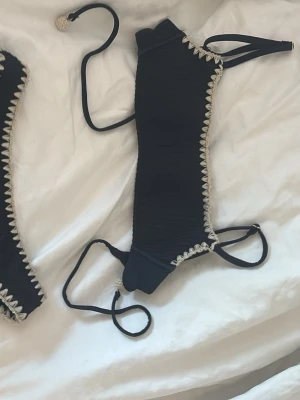 Svart bikini med virkade detaljer - Intimissimi bikini använd 2 gånger. Jätte bra skick förutom att på sidorna av bikinin så är det uppklippt men det är inget man ser för det är på insidan av bikinin. Gjorde det så jag kunde lägga ilägg. Nytt pris 850kr