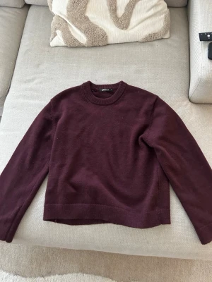 Mörkröd stickad tröja Gina Tricot - Säljer en mörkröd stickad tröja från Gina Tricot med rund hals och ribbade muddar. Tröjan har en enkel och klassisk design med långa ärmar och är gjord i mjukt material som passar perfekt till hösten och vintern.