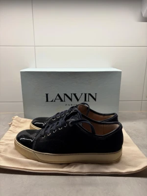 Mörkblå Lanvin sneakers  - Säljer dessa mörkblå Lanvin-skor i storlek 42. Skorna är använda och har därför vissa mindre skador, men är i övrigt i gott skick. Originalkartong och dustbag medföljer. Hör gärna av dig vid frågor. Priset kan diskuteras.