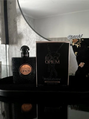 YSL Black Opium 50 ml – nästan full + kartong - Säljer min YSL Black Opium Eau de Parfum 50 ml. En feminin och omtyckt doft med varma inslag av kaffe och vanilj som ger en mjuk och elegant känsla.Flaskan är nästan full och i mycket fint skick utan några skador och har förvarats varsamt. Köpt till fullpris och originalkartong medföljer.Säljes då den inte kommer till användning.