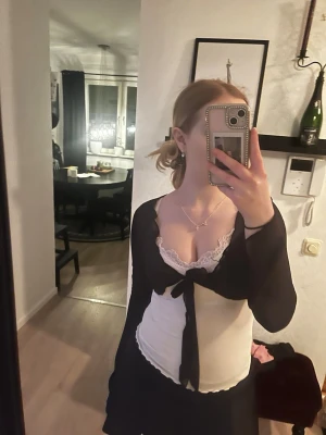 Svart bolerotopp med knyt och spets - Säljer en svart bolerotopp med knyt framtill, långärmad och i ett tunt, transparent material. Perfekt för att skapa en trendig lager-på-lager look. 