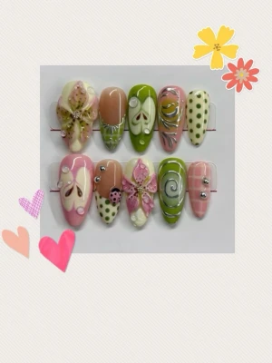 Blommiga press-on naglar i pastell - Gör dessa på beställning! Säljer ett set press-on naglar i pastellfärger med blommiga och prickiga mönster. Naglarna har mandelform och dekoreras med pärlor, blommor och små stenar. Färgerna går i rosa, grön, beige och vit. Perfekt för dig som vill ha unika och kreativa naglar!