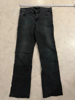 Svarta raka jeans från Replay - strl.S - Säljer ett par svarta jeans från Replay med rak passform och klassisk femficksdesign. Jeansen har bälteshällor, dragkedjegylf och är tillverkade i ett mjukt denimtyg. Perfekta för en avslappnad och stilren look.