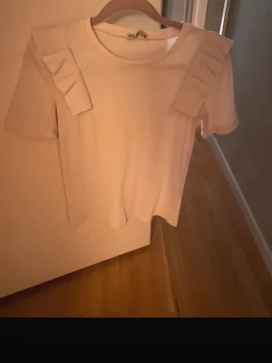 Kräm vit topp med volangdetaljer från Zara - Jätte söt kräm vit topp ifrån Zara. Använd fåtal gånger, som helt ny. 