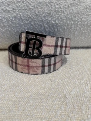 Burberry rutigt och svart bälte - Två snygga bälten från Burberry, ett i klassiskt beige, svart och rött rutigt mönster och ett i helsvart med diskret rutstruktur. Båda har en metallspänne med Burberrys ikoniska TB-logga. Perfekta accessoarer för att lyfta din outfit.Kom dm för eventuella frågor 🧐pris kan alltid diskuteras 😊