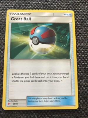 Pokémonkort Great Ball Trainer - Säljer ett Pokémonkort av typen Trainer Item med motivet Great Ball. Kortet har gul ram och färgstark illustration av en Great Ball i blått, rött och vitt. Texten på engelska beskriver kortets funktion i spelet. Perfekt för samlare eller Pokémon TCG-spelare.