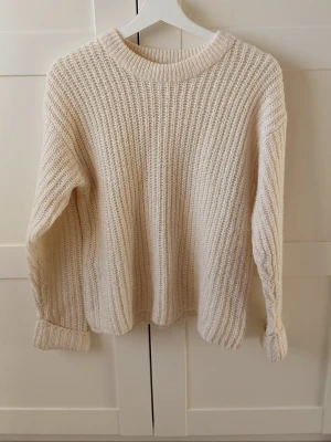 Crèmefärgad stickad tröja  - Crèmefärgad stickad tröja från NA-KD. Muddarna på ärmarna tyder på lite användning, men i helhet så är den i mycket bra skick.     Finns det nå frågor så är det bara att fråga på! 🤗