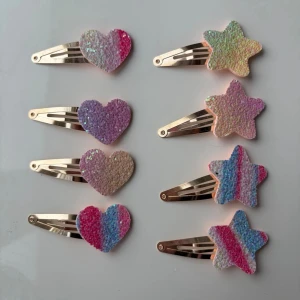 Färgglada hårspännen med hjärtan & stjärnor - Säljer åtta glittriga hårspännen i metall med dekorationer i form av hjärtan och stjärnor. Färgerna är rosa, lila, blå, beige och regnbågsfärgat. Perfekta för att piffa upp frisyren med en söt och lekfull touch.