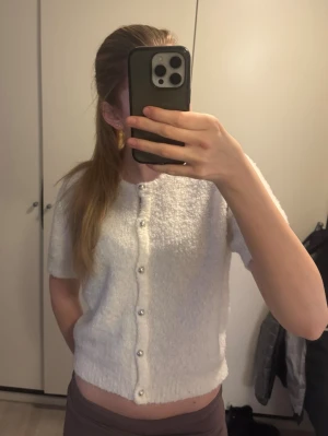 Vit kortärmad kofta med pärlknappar - Säljer denna fina kortärmade stickade koftan från Gina för den ej kommer till användning. Storlek M🥰