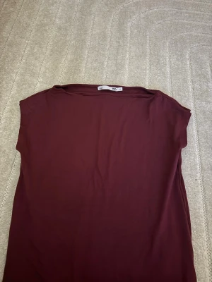 Vinröd topp från lager 157 - En enkel och stilren vinröd topp från Lager 157 Toppen har en rak passform, ärmlös design och rund halsringning. Perfekt att matcha med jeans eller kjol för en clean look.