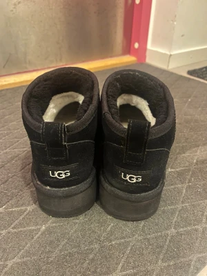 Svarta UGG stövletter i mocka - Säljer ett par svarta stövletter från UGG med mjukt, fluffigt foder på insidan. Skorna är tillverkade i mocka och har en chunky sula som ger en cool och avslappnad vibe. Perfekta för dig som gillar både stil och komfort. Nypris 1600 SEK.