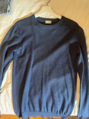 Blå stickad tröja från John Henric - Snygg blå stickad tröja från John Henric med rund halsringning och ribbade muddar. Perfekt för lager-på-lager och enkel att matcha med jeans eller chinos. Materialet är mjukt och behagligt, vilket gör den riktigt skön att bära. 100% merino 