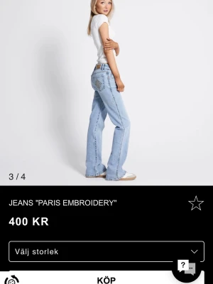 Ljusblå Paris Embroidery jeans - Säljer ett par ljusblå jeans med broderad detalj på bakfickan. Jeansen har rak passform med lätt utsvängda ben och klassisk femficksdesign. Perfekta för en avslappnad och trendig look. Materialet är denim i bomull.