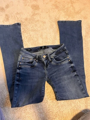 Blå bootcut jeans från LTB - Snygga blå bootcut jeans från LTB, modell Valerie. Jeansen har klassisk femficksdesign, normalhög midja och är tillverkade i ett stretchigt denimtyg. Perfekta för dig som gillar en tidlös look med lite vidare ben. Storlek 24/32 men är ganska stretchiga 