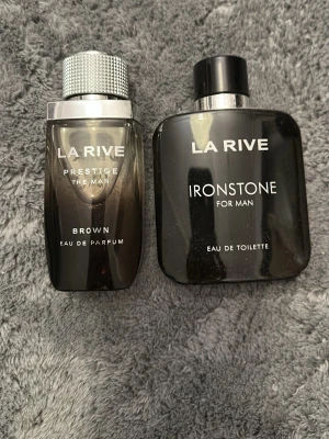 La Rive Ironstone och Brown parfym - Två herrparfymer: La Rive Ironstone For Man Eau de Toilette i svart, fyrkantig flaska med silverdetaljer och Brown Eau de Parfum i mörkbrun, avlång flaska med metalliskt lock. Båda har stilren design och passar perfekt för dig som gillar maskulina dofter.