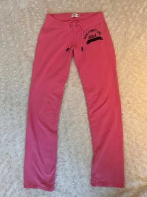 Low waisted byxor - Vintage rosa mjukisbyxor med broderad text på från abercrombie & fitch, bra skick, storlek XS (32-34) men passar även S (36)