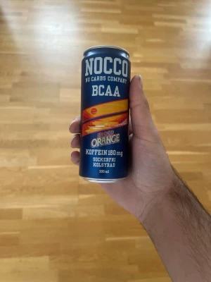 NOCCO BCAA Blood Orange 330ml - NOCCO BCAA Blood Orange är en kolsyrad dryck med koffein och BCAA, helt sockerfri. Burken är blå med orange detaljer och rymmer 330 ml. Perfekt för dig som vill ha en energiboost med fräsch blodapelsinsmak.