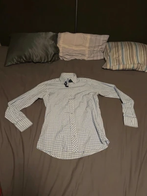 Blårutig skjorta från Polo Ralph Lauren - Säljer en klassisk blårutig skjorta från Polo Ralph Lauren i storlek S. Skjortan har lång ärm, knappar framtill och en snygg krage. Tillverkad i mjuk bomull som känns skön mot huden. Perfekt för dig som gillar stilrena och tidlösa plagg.