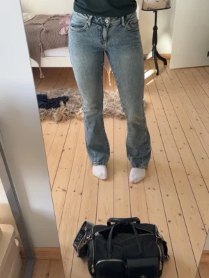 Blå bootcut jeans med hög midja - Säljer ett par blå bootcut jeans med hög midja och klassisk femficksdesign. Jeansen har en snygg tvättad look och raka ben som går ut lite nedtill. Perfekta till en avslappnad stil och passar till det mesta. Materialet är denim i bomull.