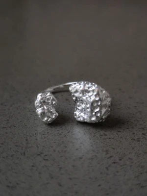 Silvrig chunky ring med rå form 925 stämpel pläterad  - Unik silvrig ring med öppen design och två stora, råa och ojämna former som ger en cool och modern känsla. Ringen har en blank yta och sticker verkligen ut med sin chunky look. Perfekt för dig som gillar statement-smycken och vill ha något annorlunda.