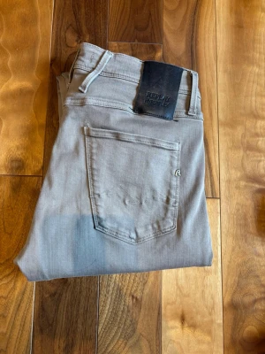 Gråa/Beige/Khaki Replay Hyperflex jeans - Beige/Khaki jeans - Replay  Replay är ett italienskt denim-märke känt för hög kvalitet och moderna passformer.  Säljer ett par snygga Replay Anbass jeans i beige/khaki  Märke: Replay  Modell: Anbass (slim fit)  Storlek: W30 L30  Färg: Beige/khaki  Replay Anbass är en populär slim fit-modell som sitter snyggt på kroppen utan att vara för tajt. Tillverkade i kvalitativ denim med lite stretch, vilket gör dem både bekväma och följsamma att bära hela dagen.  Den beige/khaki färgen gör dem enkla att m