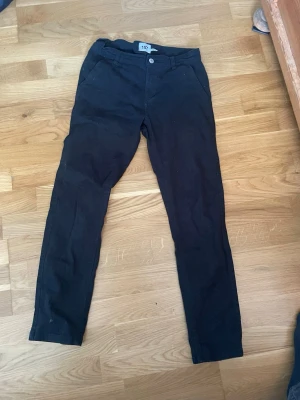 Svarta slim fit jeans från 157 - Svarta slim fit jeans från 157 med klassisk femficksdesign och knappstängning. Jeansen har raka ben och är tillverkade i ett mjukt material som ger en skön passform. Perfekta för dig som gillar en enkel och stilren look. Ser ut som ett par kostymbyxor och är jätte mjuka.