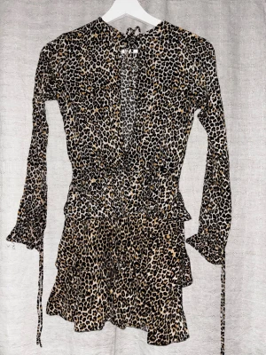 Leopard klänning - Super fin mini dress i leopard mönster med en fin urringning! knytning framtill och vid ärmarna, säljs på grund av för liten :/ Storlek S men hade sagt att den även passar Xs