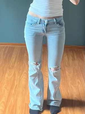 Ljusblå bootcut jeans med slitning - Superfina lågmidjade bootcut jeans.🌸🌸 Från Nelly med hål på knäna och dekorativ söm på bakfickan.