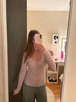 Ljusrosa ribbad tröja med knappar - Supersöt ljusrosa ribbad tröja med lång ärm och knappar framtill. Tröjan har en smickrande, figurnära passform och en djupare rundad urringning. Perfekt för dig som gillar en enkel men ändå trendig stil. Aldrig använt. Priset kan diskuteras ❣️