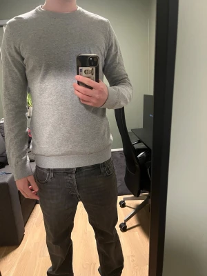 Grå stickad tröja  - En enkel och stilren grå stickad tröja med rund halsringning och långa ärmar. Tröjan har en mjuk och tunn stickning som passar perfekt till lager på lager och ger en clean look.