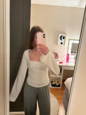 Vit långärmad topp med knyt i ryggen - Snygg vit långärmad topp med breda ärmar och söt spetskant vid halsringningen. Toppen har en öppen rygg med knytband. Perfekt att styla med jeans eller kjol. Aldrig använd o lapp finns kvar. Priset kan diskuteras❣️