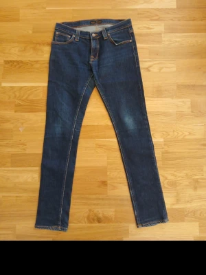 Mörkblå jeans från Nudie Jeans - Snygga mörkblå jeans från slimfit Nudie Jeans de är extremt slitna på iner lappen där det står model på byxan men skulle sägga att det är slim fit