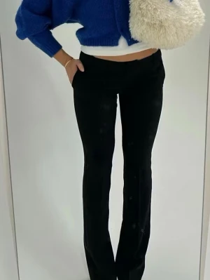 Svarta kostymbyxor med raka ben - Stilrena svarta kostymbyxor med raka ben och pressveck. Byxorna har medelhög midja, hällor för skärp och sidfickor. Perfekta för en clean och trendig look. Materialet är troligtvis en blandning av polyester och viskos för en mjuk och följsam känsla.