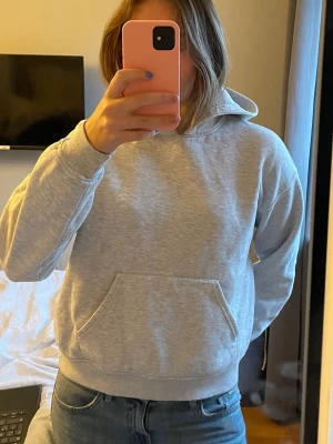 Ljusgrå basic hoodie med ficka - En stilren ljusgrå hoodie med klassisk känguruficka framtill och huva. Tröjan har ribbade muddar vid ärmslut och midja. Perfekt för en avslappnad look och passar till det mesta. Lite nopprig och har en fläck på höger ärm❣️