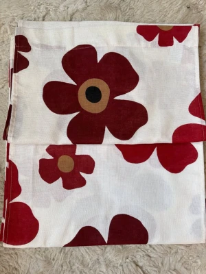 Marimekko Unikko gardinlängder - Två panellängder  Marimekko med det klassiska Unikko-mönstret i rött, svart och beige på vit botten. Tyget är i bomull och har stora blommor som ger ett färgstarkt intryck till rummet. Perfekt för dig som gillar skandinavisk design. Mått B 42 L 220.