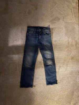 Blå jeans från Replay - Snygga blå jeans från Replay med klassisk femficksdesign och diskreta slitningar framtill. Jeansen har normal passform och är tillverkade i jeansmaterial. Perfekta för en avslappnad och trendig look.