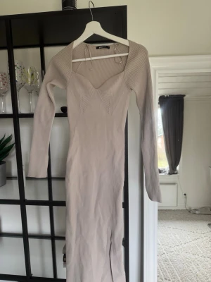 Klänning från Gina - Säljer en beige långklänning från Ginatricot med ribbad struktur och v-ringad hals.