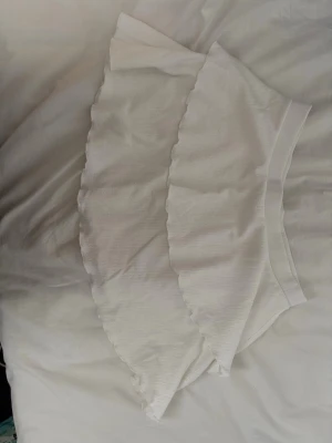 Vit volangkjol från 157 - Säljer en söt vit kjol från 157 i storlek M 🌸volangkant och elastisk midja🌸Kjolen är kort och har en lätt struktur i tyget🌸Aldrig använd🌸