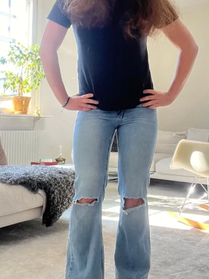 Ljusblå bootcut jeans med slitningar - Säljer dessa eftertraktade somriga ljusblå jeans med slitna hål på båda knäna. Jeansen är i storlek 146 men passar mig som vanligtvis har xs-s och är 157 cm.