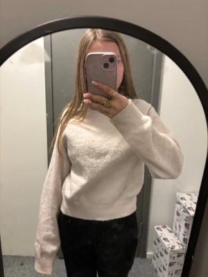 Ljusrosa stickad tröja - Mysig rosa stickad tröja med rund hals och långa ärmar. Tröjan har ribbade muddar vid ärmslut och nederkant, och är tillverkad i ett mjukt material som passar perfekt för kyligare dagar. Enkel och stilren design som är lätt att matcha.